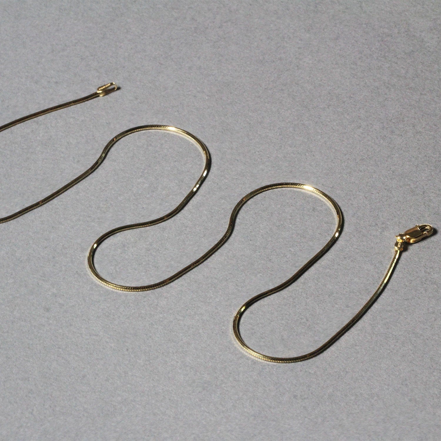 1.0mm 14K Yellow Gold Octagonal Shiny Snake Chain in a sleek high-contrast midnight luxury editorial style