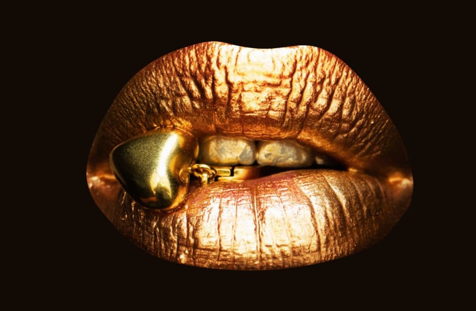 Womans golden lips close up isolated background Isolated gold mouth Jewelry concept