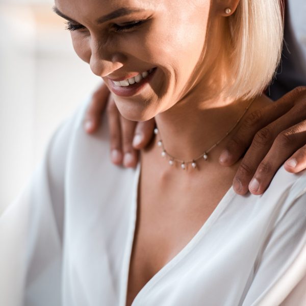 cropped view man putting hands on shoulders of cheerful woman