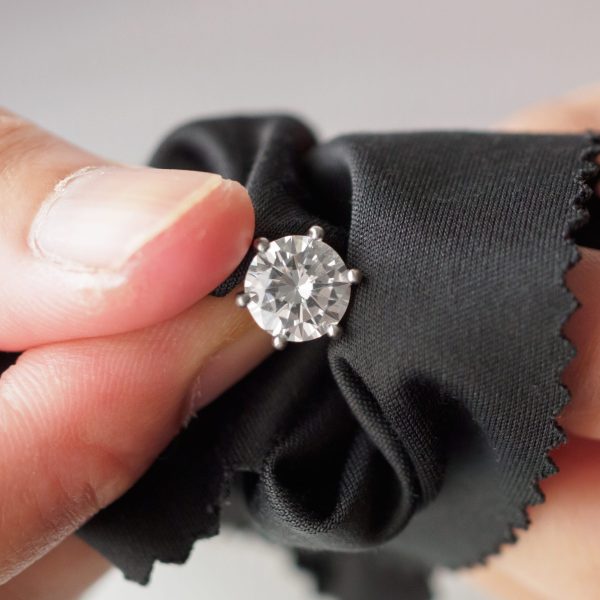 Jeweller cleaning jewelry diamond ring with fabric cloth